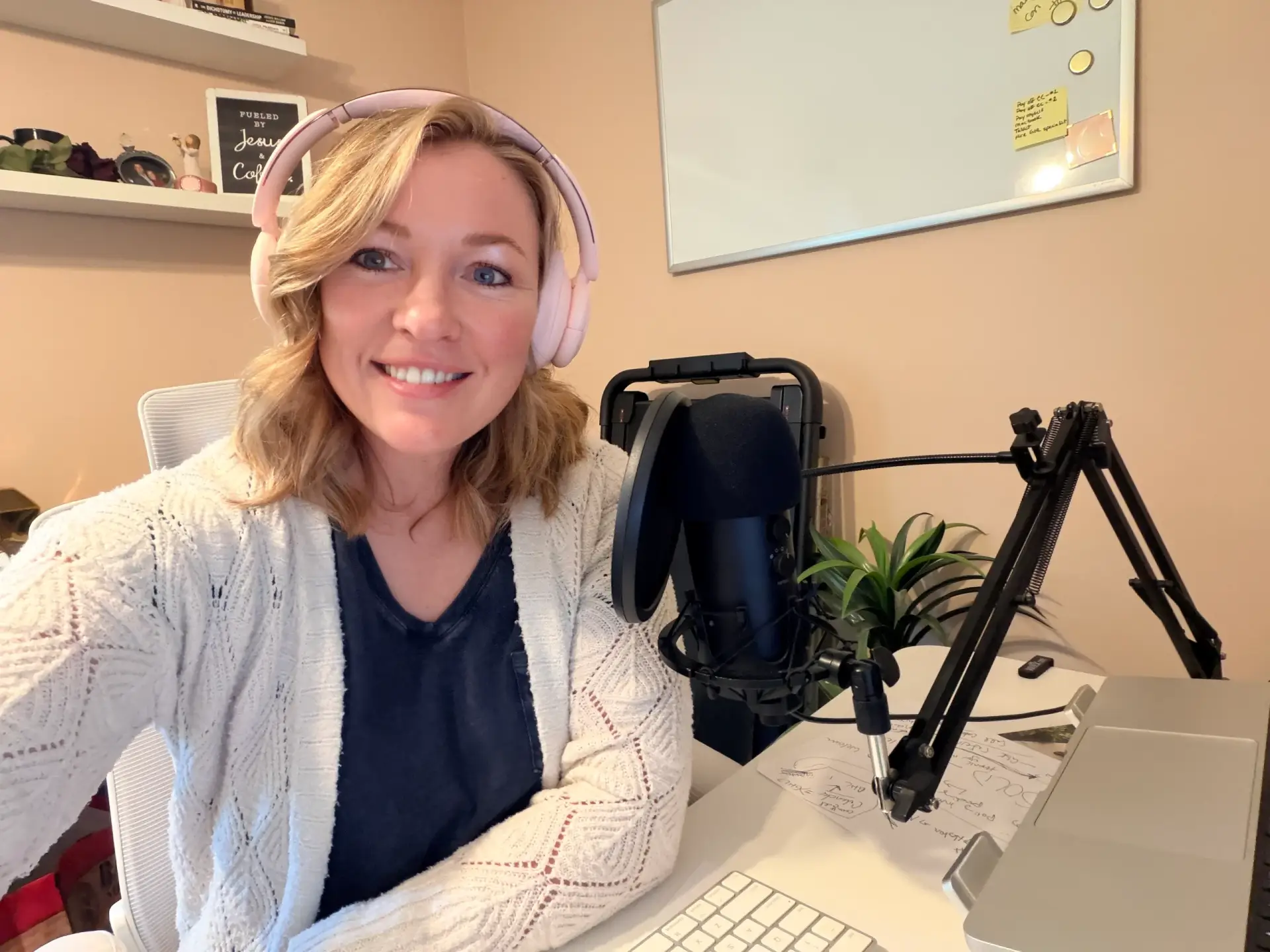 Raney Day Design founder and business strategist, Jennifer Sakowski, sits at her desk with a microphone and laptop computer while wearing headphones