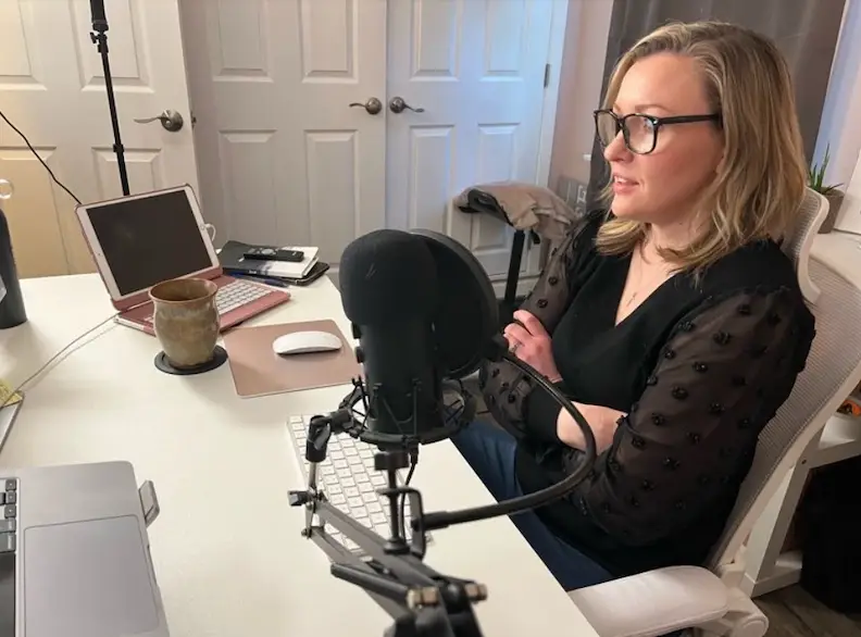 Jennifer Sakowski sits at her desk in her office, preparing to record a podcast